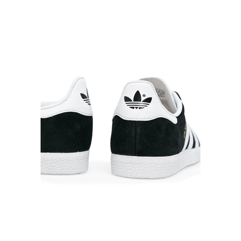 Adidas women black sneakers with black and white suede upper, rubber sole, lace up, and iconic three stripes