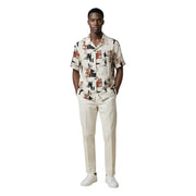 Un homme portant un Antony Morato chemise homme à manches courtes boutonnée avec imprimé abstrait de paysage urbain beige, noir et rouille