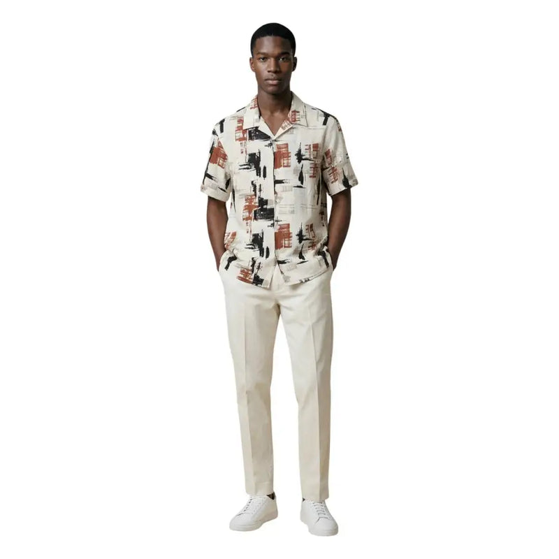 Un homme portant un Antony Morato chemise homme à manches courtes boutonnée avec imprimé abstrait de paysage urbain beige, noir et rouille