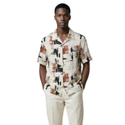 Un homme portant un Antony Morato Chemise homme à manches courtes avec motif géométrique noir et orange rouille sur fond crème