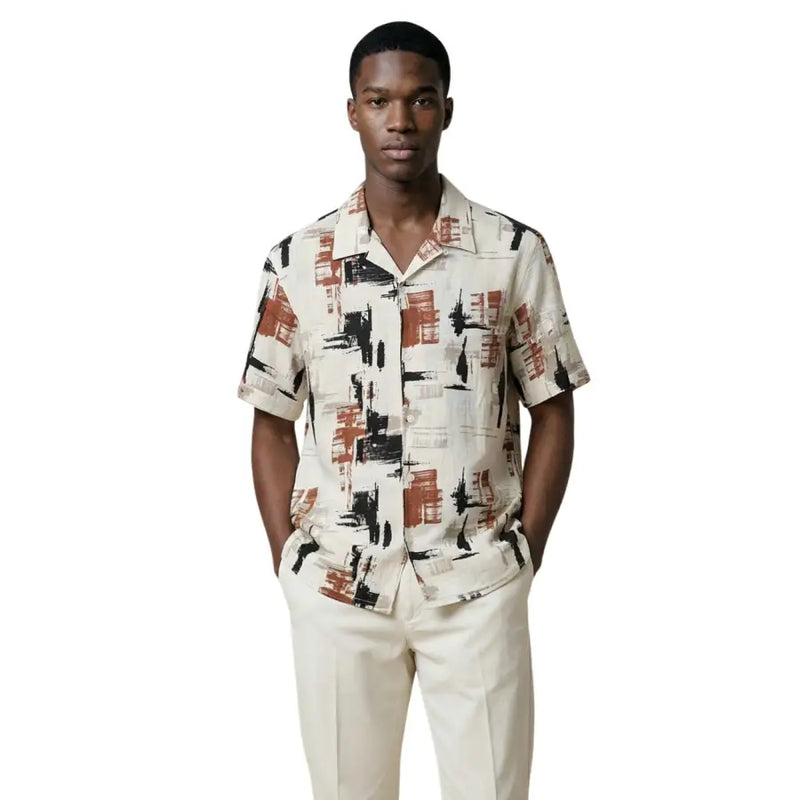 Un homme portant un Antony Morato Chemise homme à manches courtes avec motif géométrique noir et orange rouille sur fond crème