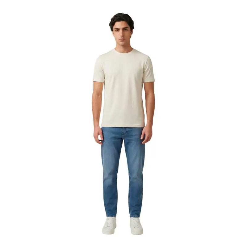 Ein Mann, der einen antony morato Männer t-shirt in Creme mit kurzen Ärmeln und Rundhalsausschnitt, kombiniert mit mittelblauen Jeans