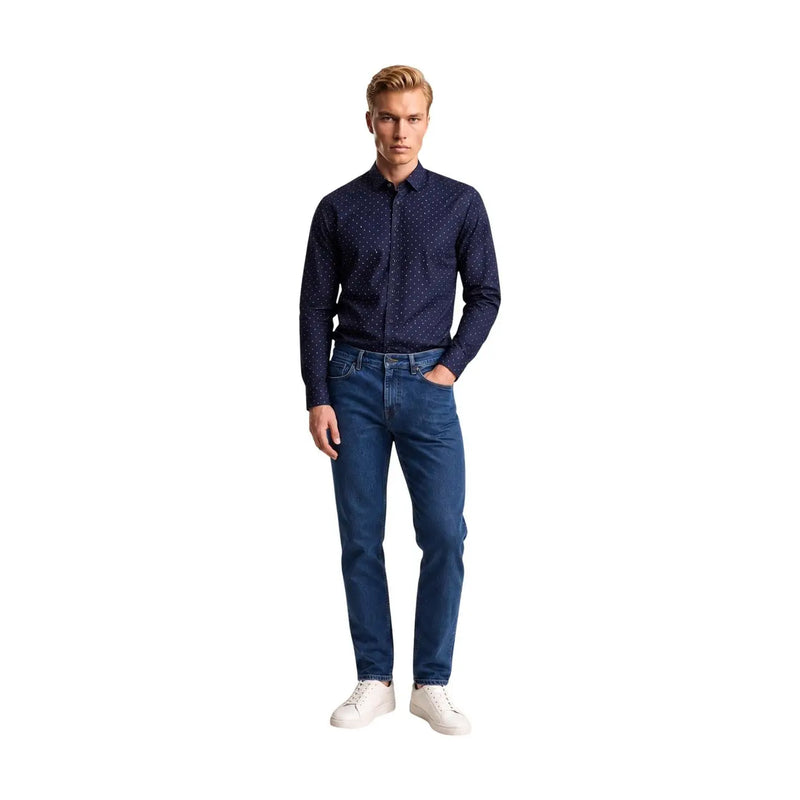 Ein Mann, der einen armani exchange Herrenhemd aus blauer Baumwolle mit geometrischem Muster und weißen Punkten sowie klassisch geschnittene Jeans
