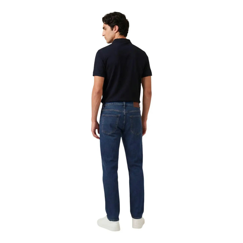 Dark blue denim jeans with five-pocket design and brown leather patch paired with armani exchange men blue zip polo