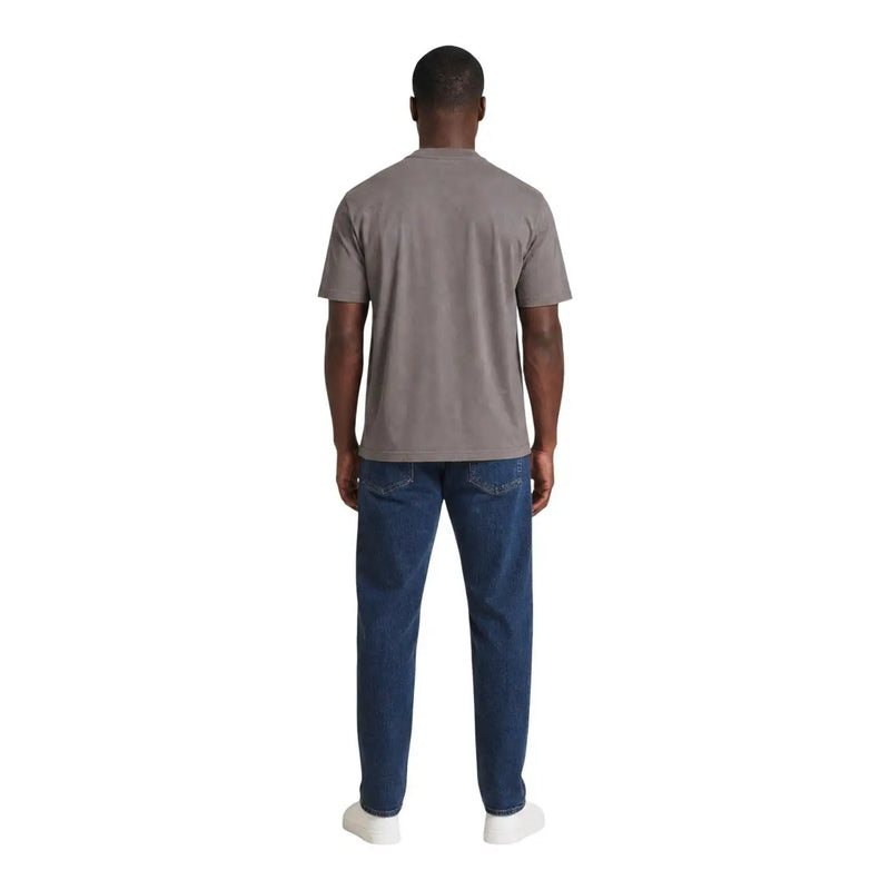 A man wearing an Armani Exchange men brown cotton t shirt paired with dark blue jeans