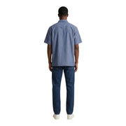 A man wearing an armani exchange light blue short-sleeved cotton shirt and dark wash denim jeans