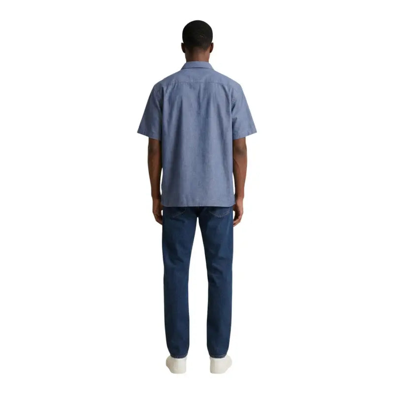 A man wearing an armani exchange light blue short-sleeved cotton shirt and dark wash denim jeans