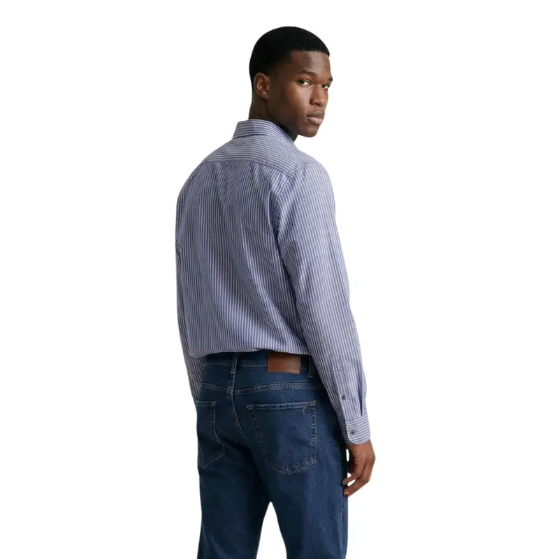 A man wearing an Armani Exchange men shirt in blue and white striped long-sleeved button-down style