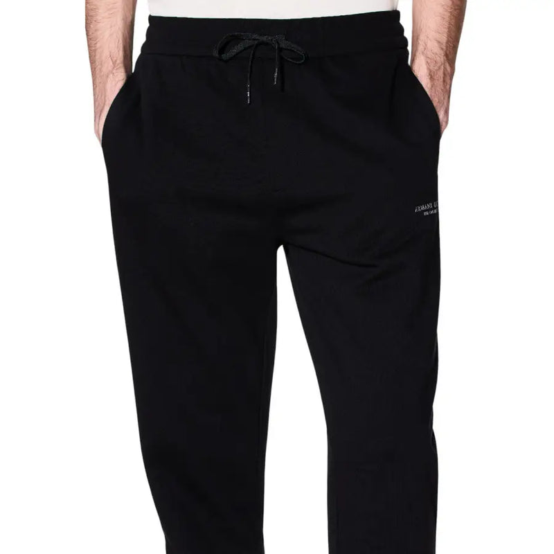 Black cotton armani exchange men trousers featuring joggers design with drawstring waistband and white branding on thigh