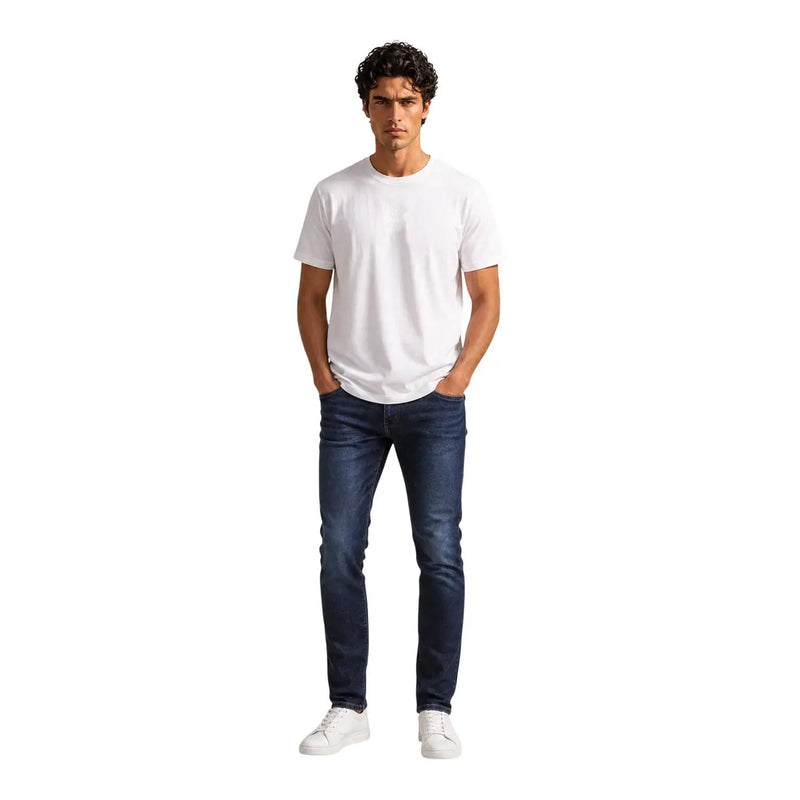A man wearing an Armani Exchange men white cotton t shirt with a plain white crew neck and dark blue slim-fit jeans