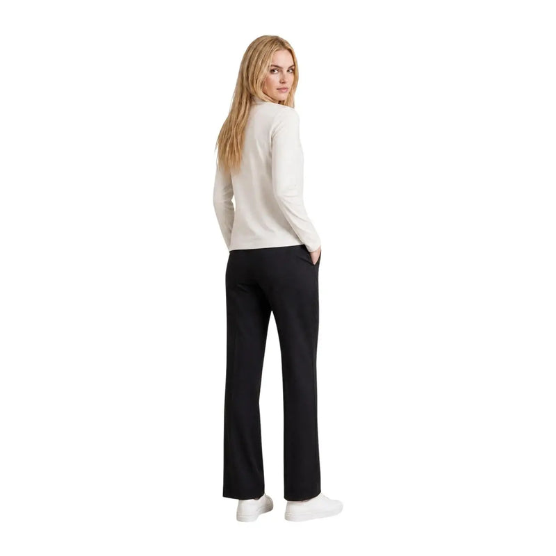 A woman wears an Armani Exchange women beige cotton rhinestone t shirt paired with black trousers and white sneakers