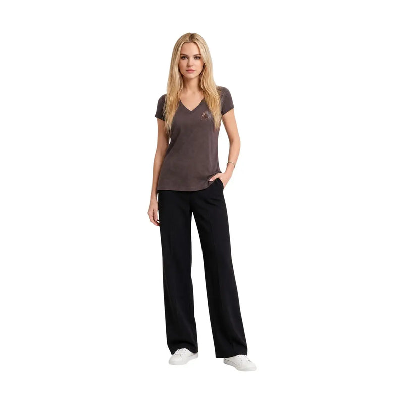A woman wearing an Armani Exchange women brown cotton v neck paillettes t shirt paired with black trousers and white sneakers