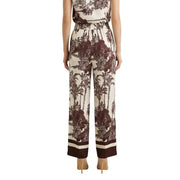 Cream-colored silk wide-leg pants with bold brown tropical print and striped cuffs from artigli spring summer collection