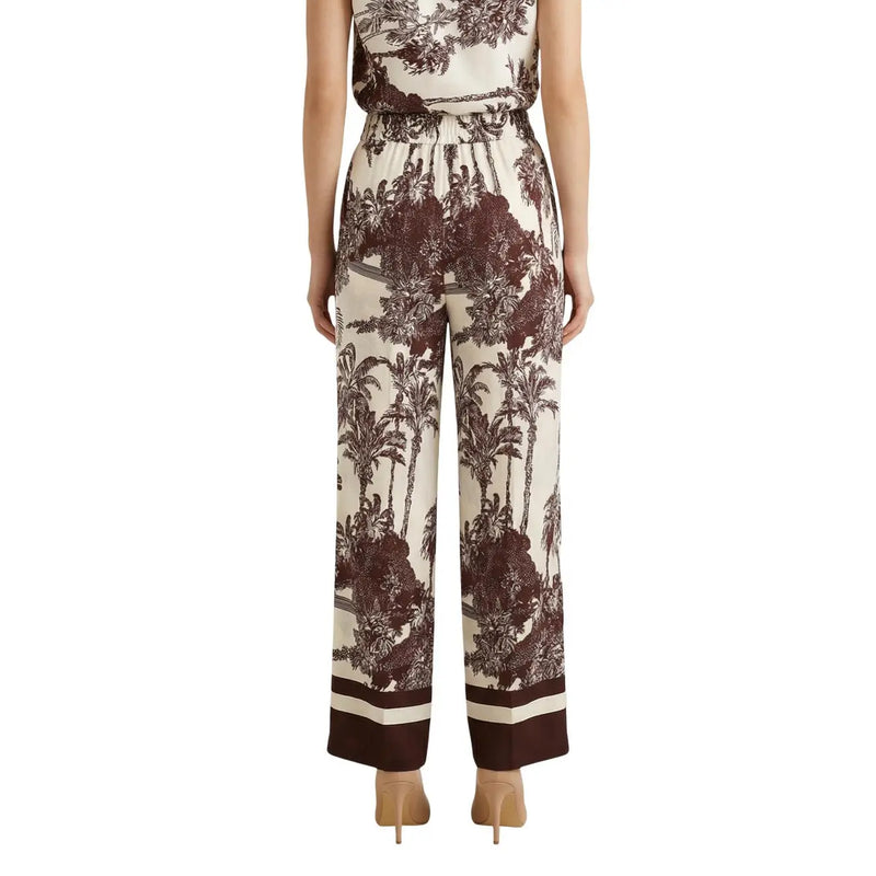 Cream-colored silk wide-leg pants with bold brown tropical print and striped cuffs from artigli spring summer collection