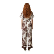 A woman wears an Artigli women floral jumpsuit beige viscose with brown botanical print, flutter sleeves, and wide legs