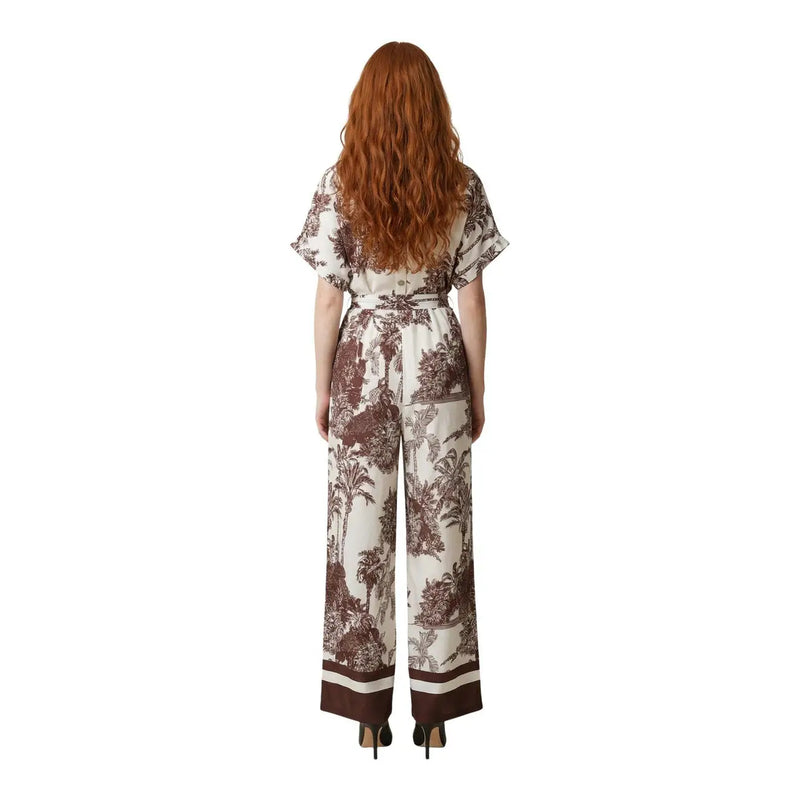 A woman wears an Artigli women floral jumpsuit beige viscose with brown botanical print, flutter sleeves, and wide legs