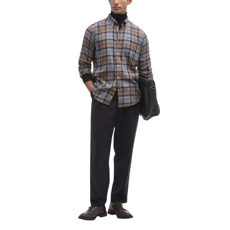 A man wearing a Barbour men shirt in brown gray and beige plaid with black cuffs and button-down design