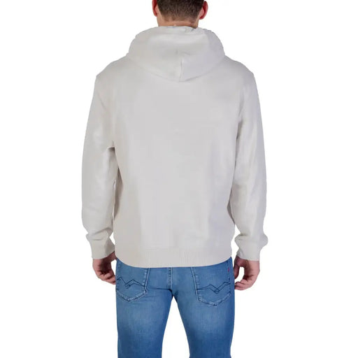 Men’s beige Calvin Klein hooded sweatshirt with front pocket paired with blue jeans