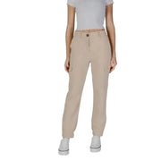 Beige cargo pants with pockets styled with a white crop top and white sneakers