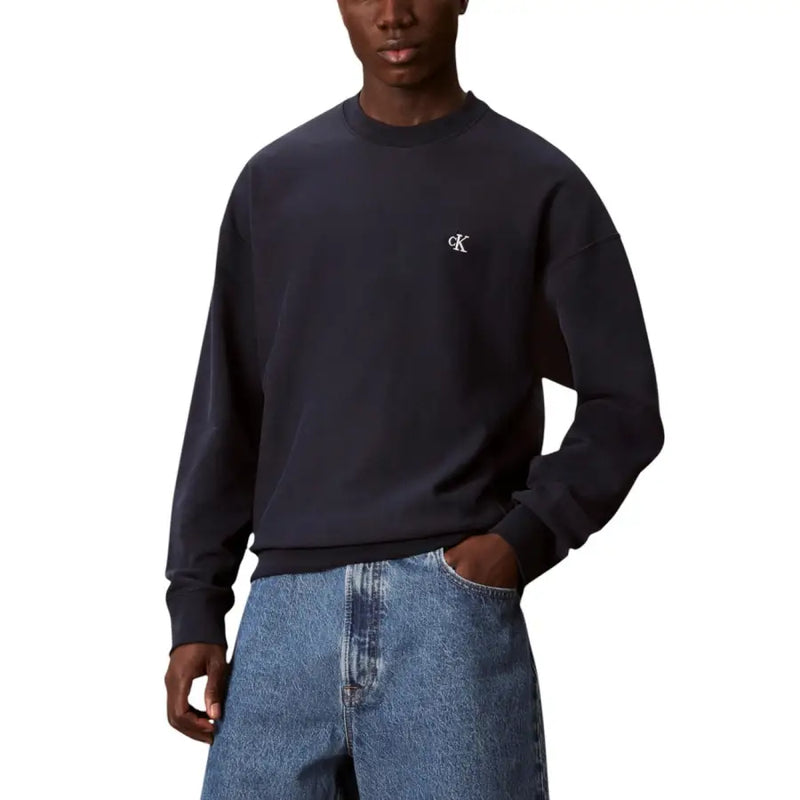 Beige crewneck sweatshirt featuring a dark navy calvin klein sweatshirt with a small white embroidered logo on the chest