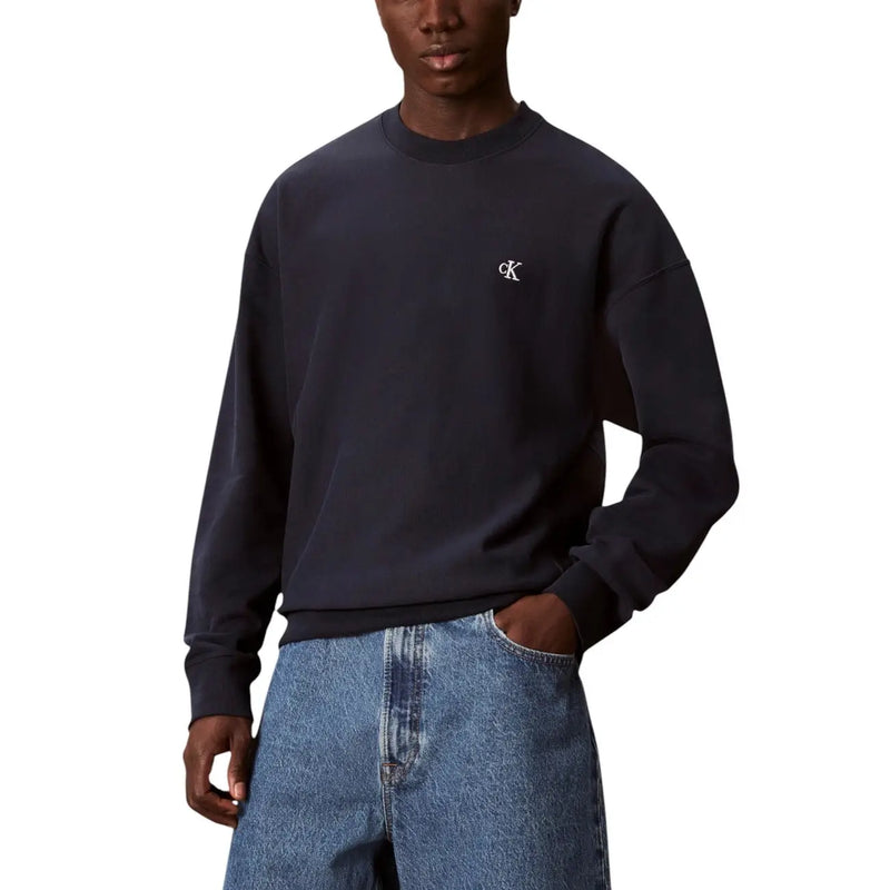 Beige crewneck sweatshirt featuring a dark navy calvin klein sweatshirt with a small white embroidered logo on the chest