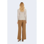 A woman wearing a beige round neck long sweater paired with wide-leg camel trousers showcasing the front view
