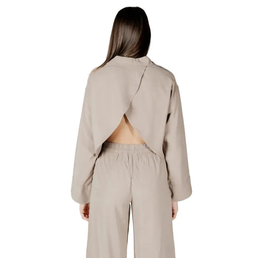 Beige viscose long sleeve round neck cropped blouse for women with a distinctive back cutout shown from the back side