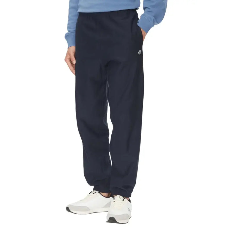 Schwarze Calvin Klein Jogginghose mit elastischen Bündchen und dunkelblauem Bein mit dezentem weißen Logo am linken Bein