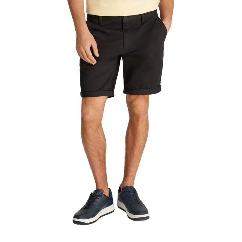 Black chino shorts worn by a man paired with a yellow T-shirt in casual style