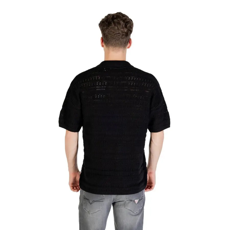 Black knit polo shirt showing back side with textured openwork pattern and short sleeves in a knitted fabric