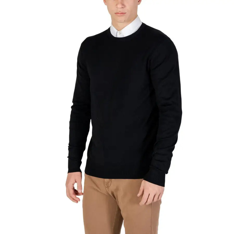 Black crew neck sweater with white collar and beige pants.