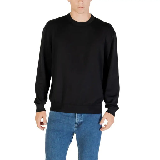 Black long sleeved crewneck sweater made of soft fabric featuring ribbed cuffs for a comfortable fit