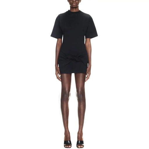 Black short-sleeved mini dress with high neckline and gathered waist detail paired with sculptural heels