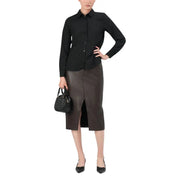 Black quilted handbag with structured shape and top handle on polka dot shirt