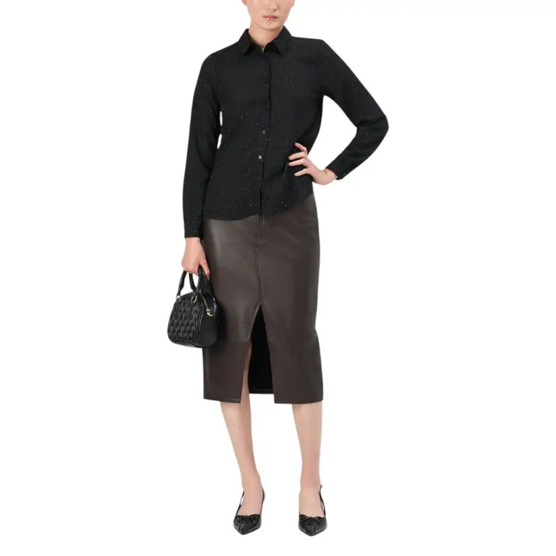 Black quilted handbag with structured shape and top handle on polka dot shirt