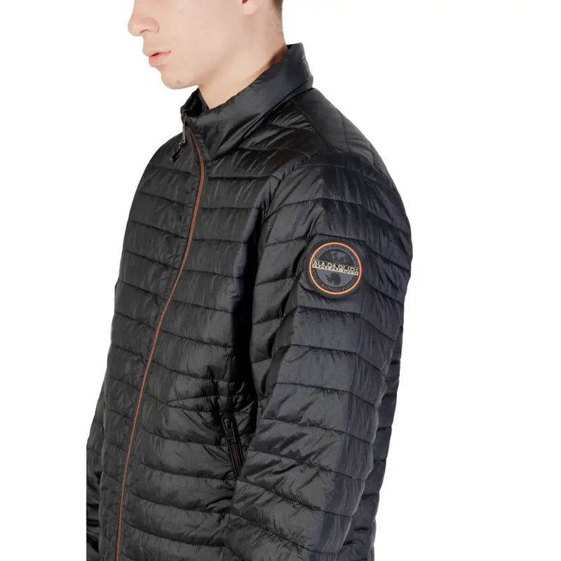Black quilted puffer jacket with circular patch on sleeve and orange zipper accents for cold weather use