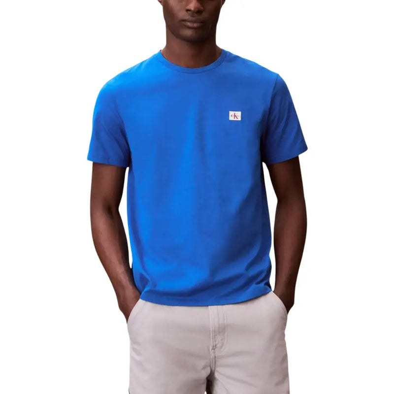 Black short sleeve crewneck t-shirt featuring a bright blue Calvin Klein fabric with a small white logo patch on the left chest