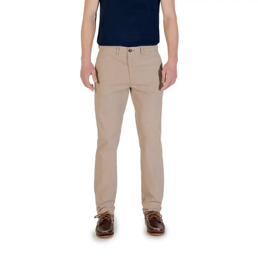 Men’s beige chino trousers paired with navy polo shirt and brown boat shoes for spring summer fashion