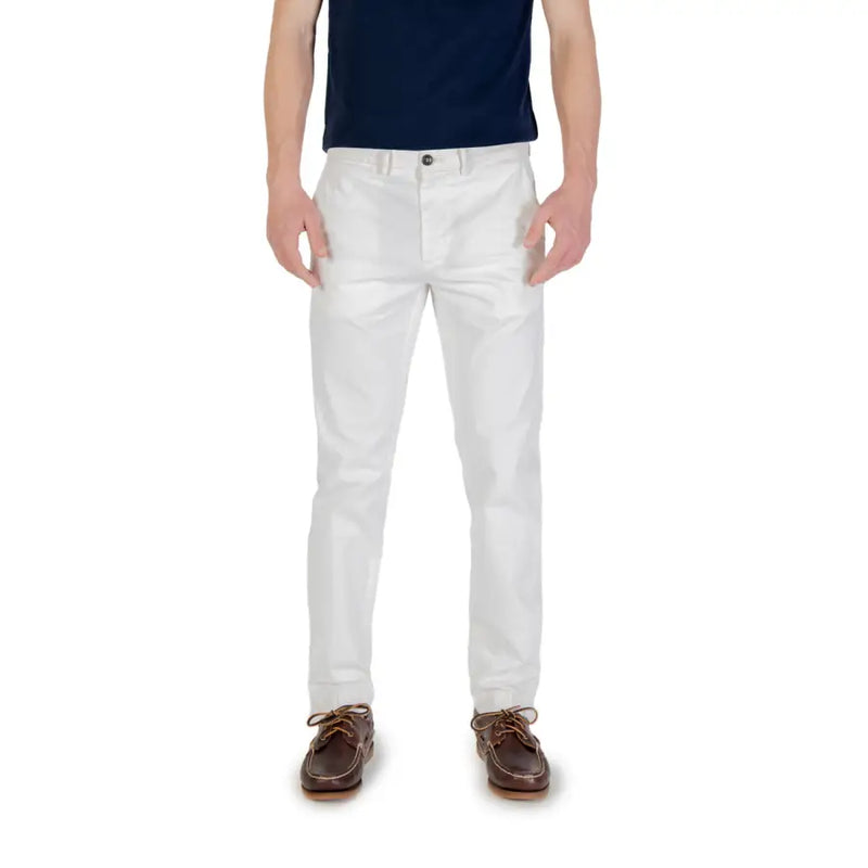 Men’s white chino pants paired with a dark blue t-shirt and brown boat shoes