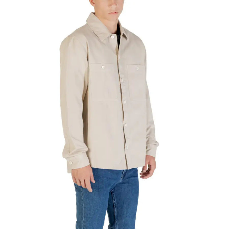 Men’s light beige long-sleeved button-up shirt with chest pockets paired with blue jeans