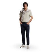 A man wearing a boss men polo shirt grey cotton zip neck short sleeve with navy slim-fit jeans and white sneakers