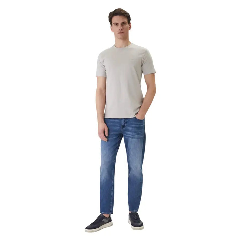 Ein Mann trägt ein graues Boss Men T-Shirt von Grey Tales mit Rundhalsausschnitt und kurzen Ärmeln aus Baumwolle in Hellgrau und dazu blaue Jeans.