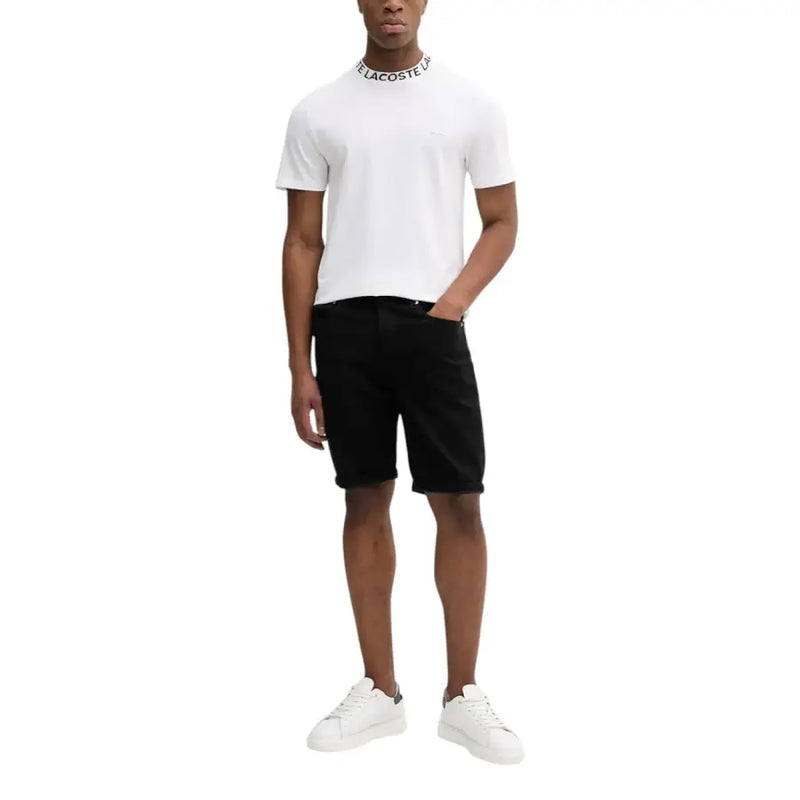 Polo Lacoste blanc, short noir et baskets blanches.
