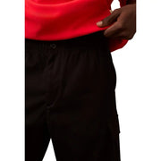 Person wearing red sweatshirt and black cargo pants from Calvin Klein Jeans Black Fall Winter collection