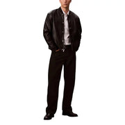 Men’s black leather bomber jacket paired with white collared shirt, black trousers, and dress shoes