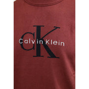 Calvin Klein Jeans Pull en coton bordeaux pour homme, orné du logo CK noir et de broderies blanches (vue de face).