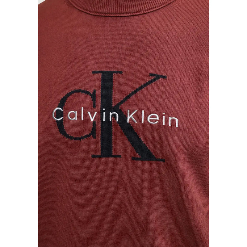 Calvin Klein Jeans Pull en coton bordeaux pour homme, orné du logo CK noir et de broderies blanches (vue de face).
