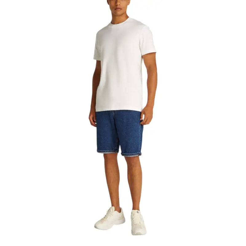 White crew neck t-shirt with blue denim shorts and white sneakers.