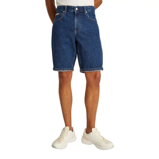 Blue denim shorts with rolled hem and white sneakers