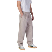 Person wearing beige pleated trousers and white sneakers with green stripes for Calvin Klein Jeans Men